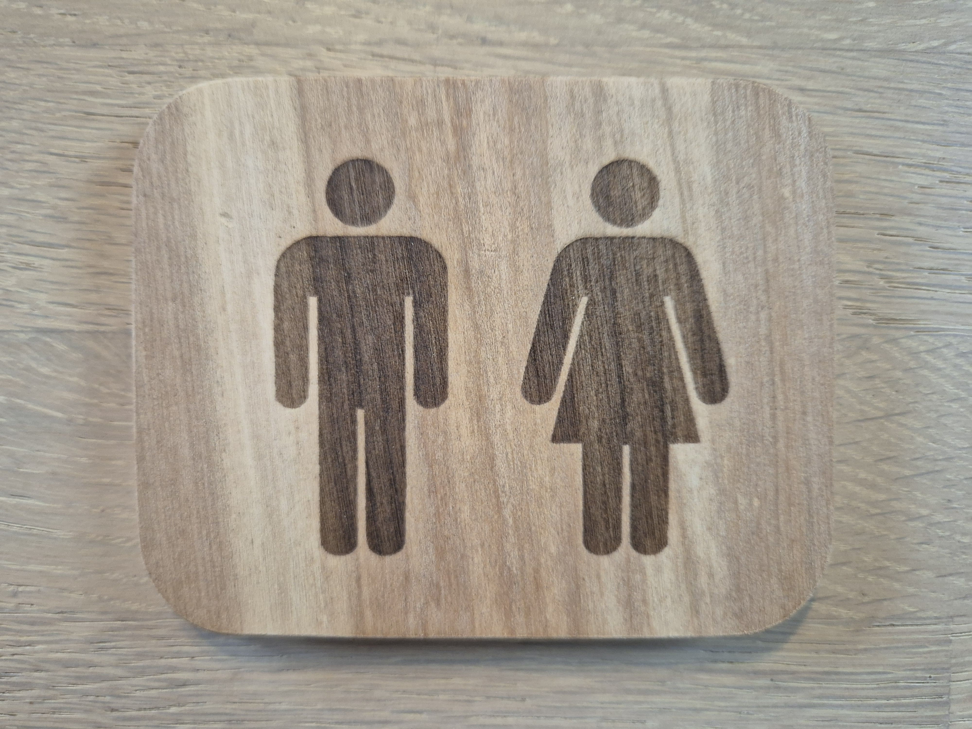 Schild mit gravierten WC-Piktogrammen im Format 10x8 cm auf Birkenholz.